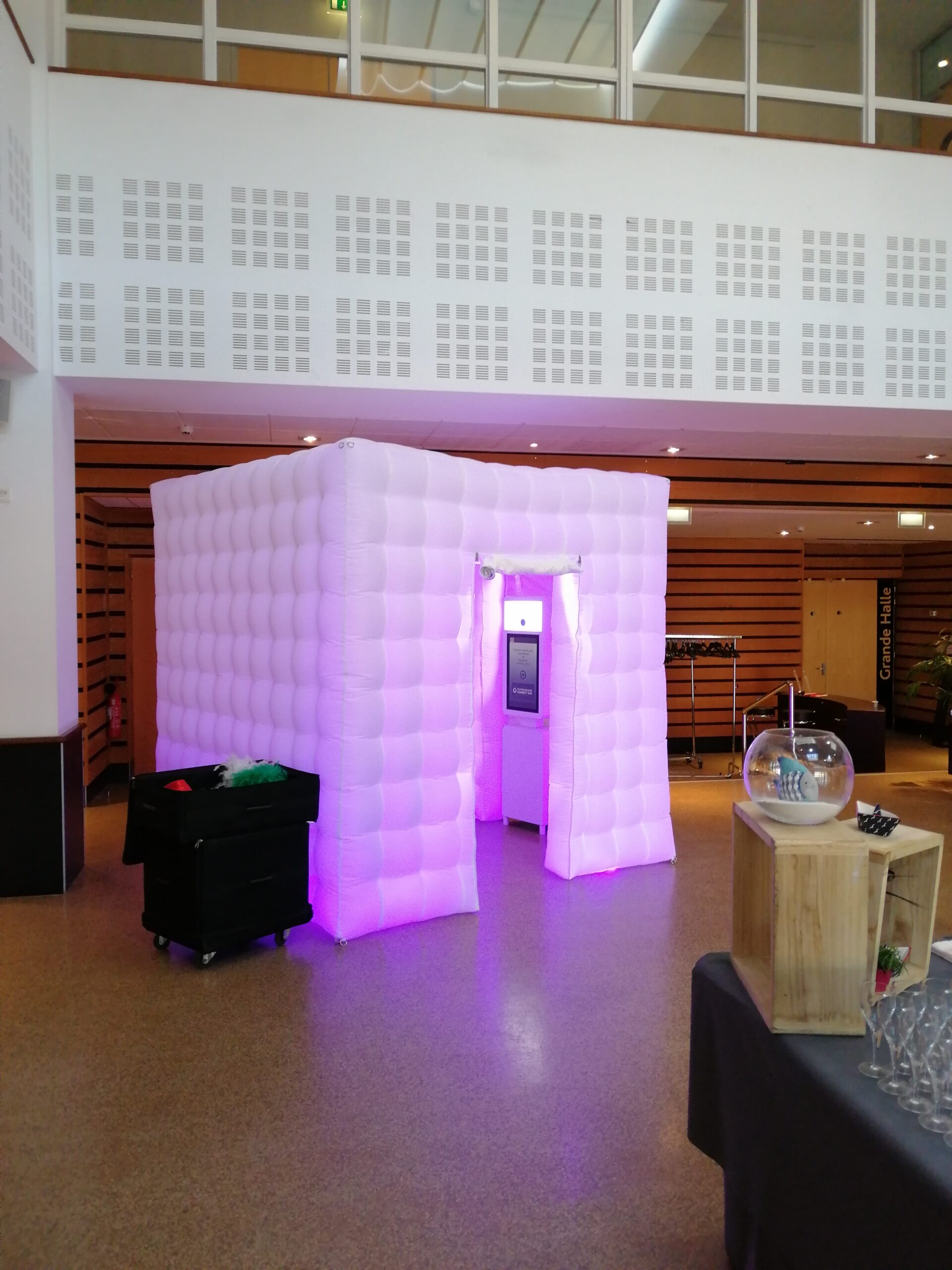 Cabine photo gonflable blanche éclairée en violet, installée lors d’un événement
