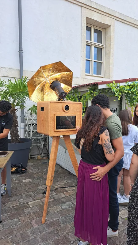 Un couple utilisant le photobooth avec son parapluie doré lors d’une réception en extérieur