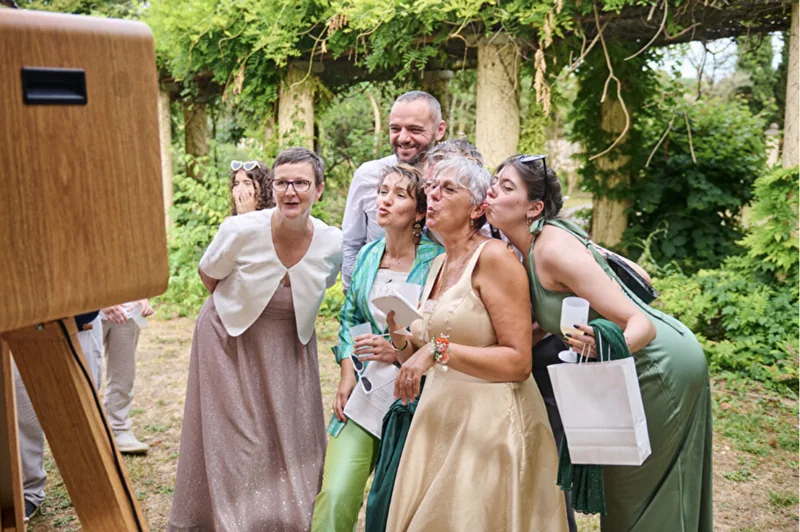 Des invités prenant la pose ensemble devant la borne à selfie dans un jardin