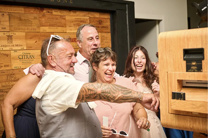 Un groupe d’invités souriant devant le photobooth lors d’une réception en intérieur